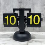 Horloge à pages flip rétro noire sur plan de travail marbre, affichant 10:10.