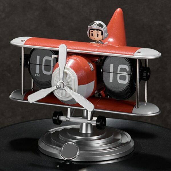 Horloge flip avion mécanique rouge avec pilote, design rétro et chiffres 10:16, posée sur socle métallique. Horloge flip avion mécanique rouge avec pilote, design rétro et chiffres 10:16, posée sur socle métallique.