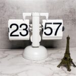 Horloge flip rétro blanche affichant 23:57 sur un socle marbre, accompagnée d'une mini tour Eiffel dorée.