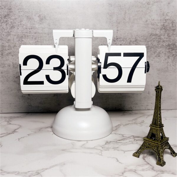 Horloge flip rétro blanche affichant 23:57 sur un socle marbre, accompagnée d'une mini tour Eiffel dorée.
