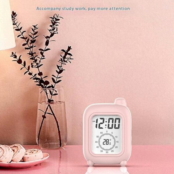 Réveil de voyage rose avec écran numérique affichant 12:00 et 28.6°C, posé près d'un ordinateur. Réveil de voyage rose avec écran numérique affichant 12:00 et 28.6°C, posé près d'un ordinateur.