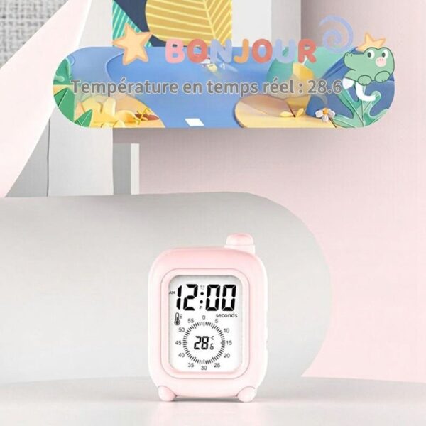 Réveil de voyage rose sur un bureau décoré, avec texte 'HELLO' et affichage de la température en anglais.