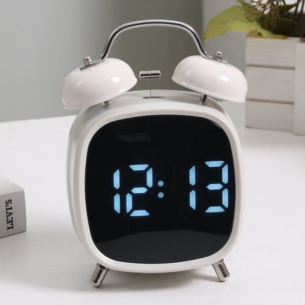 Réveil double cloche blanc avec affichage LED bleu, posé sur une table blanche.