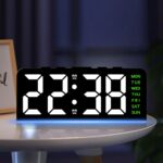 Réveil numérique LED noir sur table de chevet, affichage lumineux blanc avec lumière d'ambiance bleue.